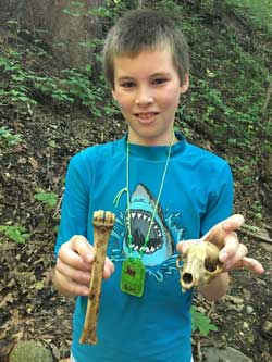 young boy holding scull and leg bone of animal
